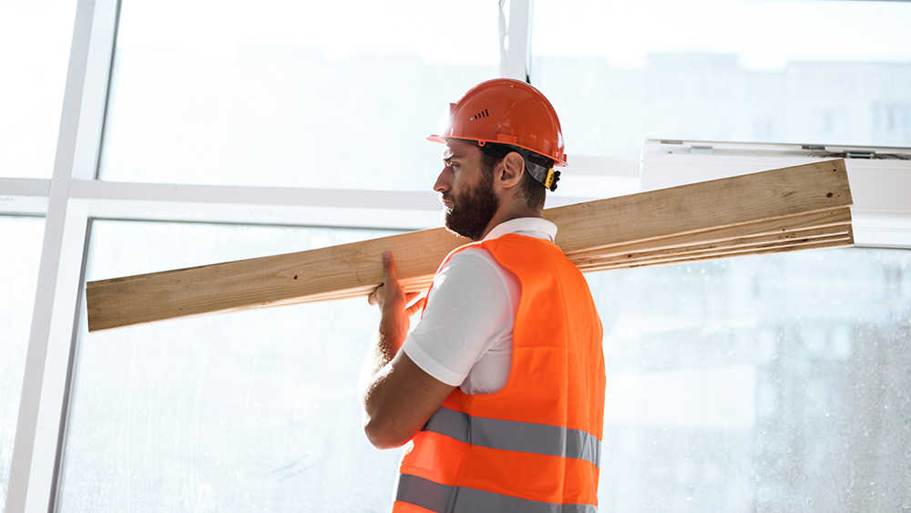 647888ca92d03e3fca3f245a builder man in hardhat carrying timber on building 2021 10 14 17 49 28 utc