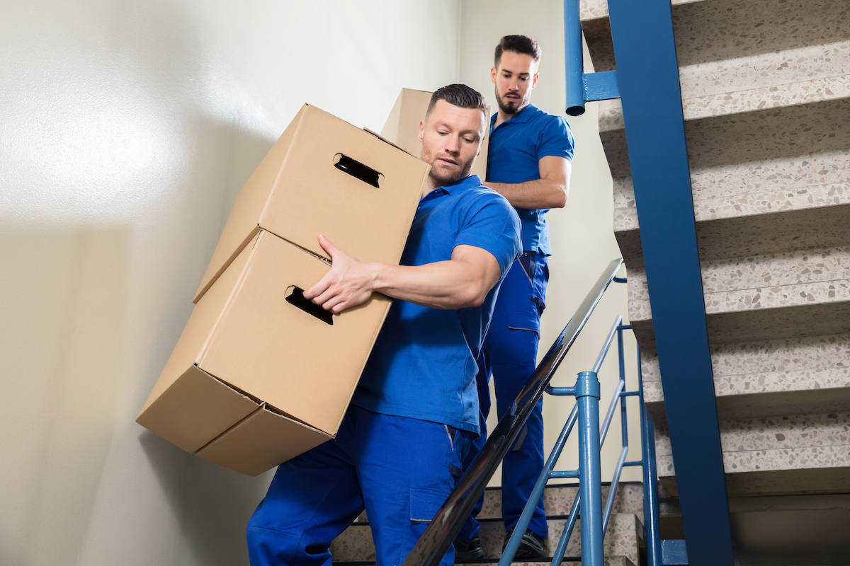 two men holding boxes while walking down stairs