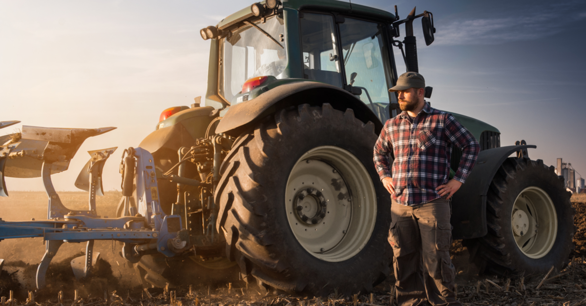 man in plaid standing in front of tractor
